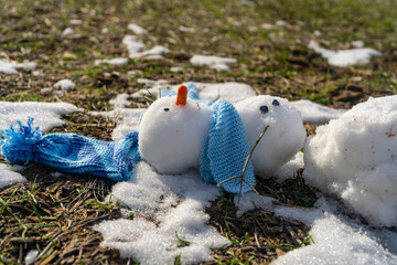 Obraz premium Snowman melting in warm winter or spring weather. Melted snowman as a symbol of warm winter spring. Winter and spring seasons change. Melting snowman with puddles around it. From winter to spring.