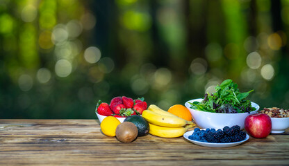 Breakfast served on wooden table. Fresh muesli with yogurt, fruit, and berries. Granola with milk and honey. Oatmeal with juicy berries. Healthy eating concept with organic food and fiber on green.