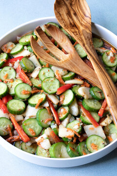 Large bowl of Asian Cucumber, Pear  and Red Pepper Salad with dressing and tongs for serving