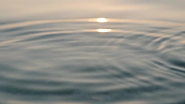 Water droplet splashing into calm lake surface at golden hour, minimalistic nature concept with copy space