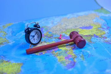 Red gavel and black stopwatch on world map symbolize global justice, legal urgency, and international decision-making across geographic boundaries.