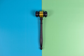 Judge gavel and pink ribbon on split blue-green background, symbolizing justice and breast cancer awareness through contrasting visual elements.