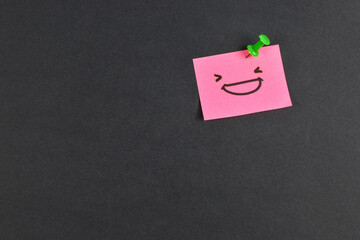 Yellow and pink sticky notes with smiley faces on black background, expressing emotion and contrast through minimal design and color.