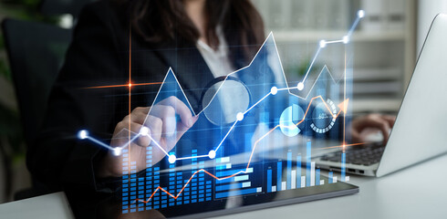 A professional woman analyzes data trends on her laptop, with dynamic graphs and charts displayed in the background, highlighting a modern business environment. Scalp