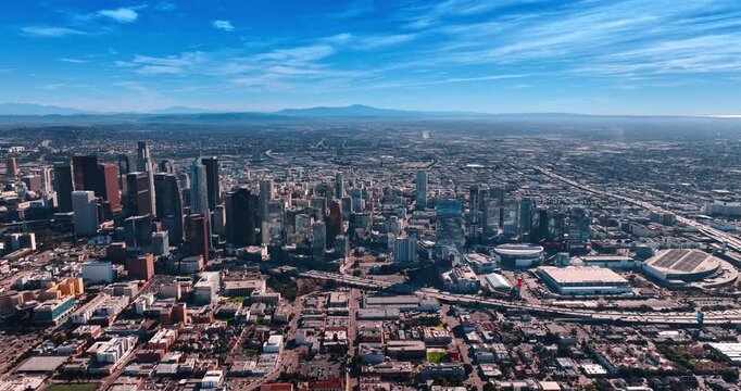 Highways leading to the city downtown are filled with moving cars. Vast panorama of sunny Los Angeles, California, USA from drone.