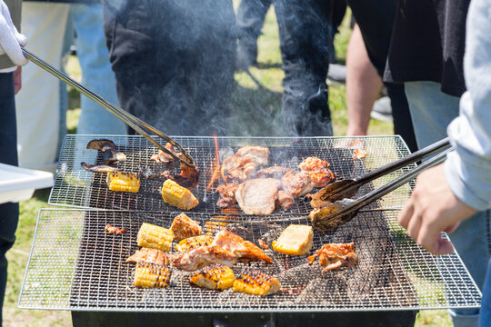 野外でのバーベキュー風景 炭火で焼く肉とトウモロコシのシズル感