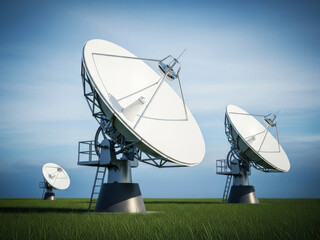 Three large satellite dishes on a grassy field under a blue sky with clouds
