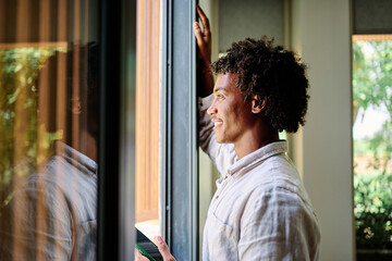 Portrait of a young black man chatting with girlfriend at home, using modern mobile phone, checking social media, using mobile app, texting or browsing internet on his phone in bedroom at home