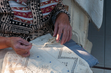 Obraz premium Senior Woman creating delicate traditional lefkara lace, a detailed handicraft from cyprus, preserving cultural artisan skills. Handmade art craft