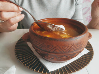 Solyanka mixed meat. Female hands holding a spoon with solyanka soup close-up