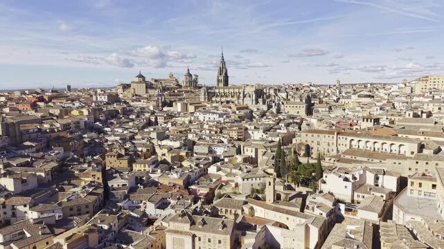 Wide drone establishing shot flying low over the city of Toledo, Spain with slow tilt up. Aerial HDR 4K/60fps footage moving towards the historic cathedral at the city center.