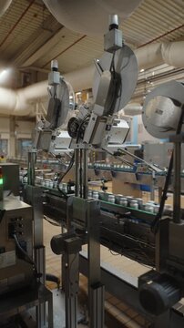 Automated labeling machine above bottle conveyor in industrial factory