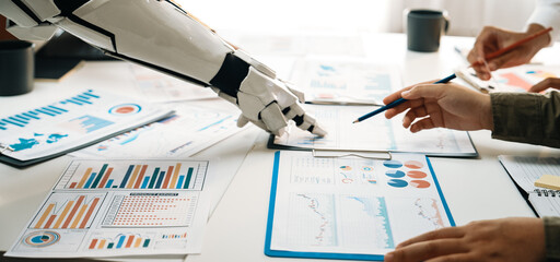 A robotic arm interacts with business analytics documents on a table, showcasing collaboration...
