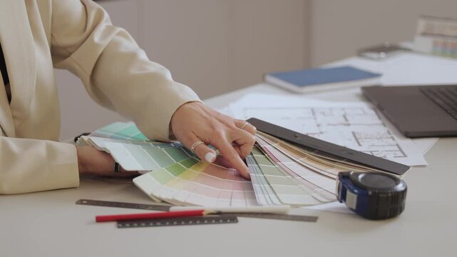 Designer organizing color swatches on desk for project planning.