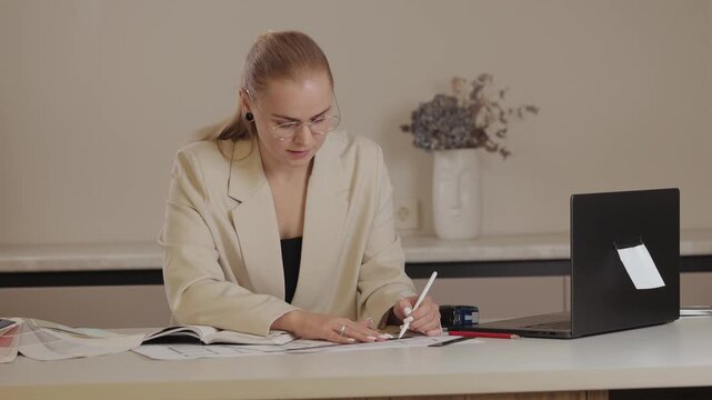 Female architect reviewing architectural plans in office setting, top view.