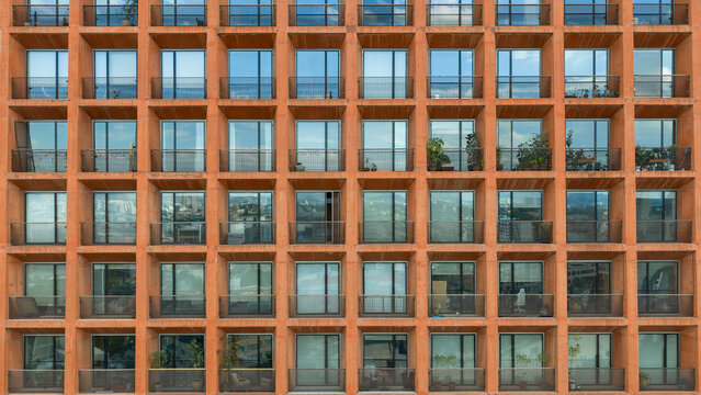 modern building with a repetitive grid facade, square balconies, and large glass windows. Clean lines and modular architecture expressing contemporary urban design.