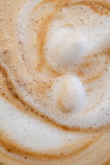 Abstract coffee texture created by milk foam and espresso crema, warm tones and organic swirl pattern.