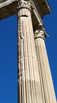 perspective tall corinthian columns topped intricately carved entablature stands boldly against deep cloudless blue sky rome upward empire dramatic 