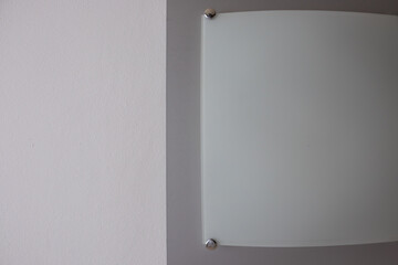 Minimalist wall lamp mounted on a light painted wall. Simple modern interior detail with empty space and neutral tones. No people.