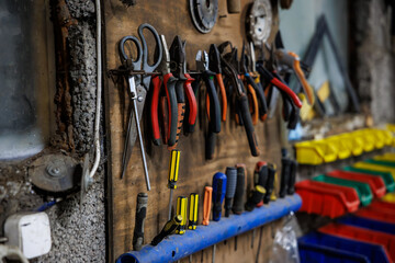 Close view of a workshop pegboard shows pliers, snips, scissors, side cutters, and insulated...