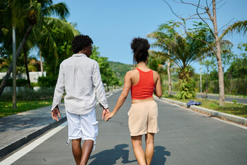 Fototapeta premium Portrait of a young couple at the beac in summertime, a man and a woman are playing with a blue towel on the beach