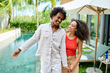 Young couple walking, bonding and enjoying a summer party by a pool, vacation love and bonding...