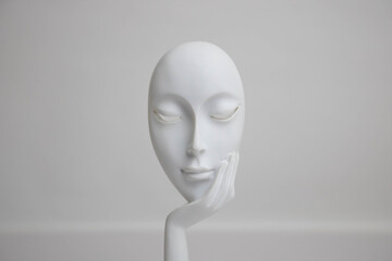 A white statue with a young girl's face resting on her palm