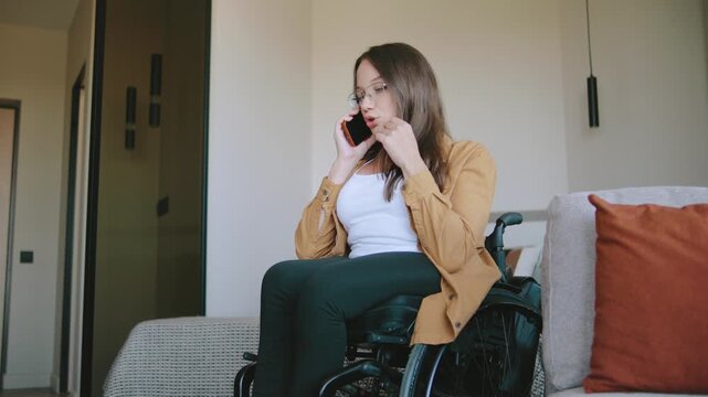 A serious woman in a wheelchair is swearing discontentedly on the phone