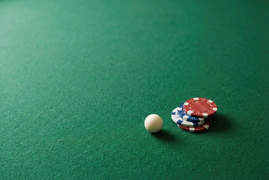 Poker chips and a cue ball sit on a green table during a game night with friends in a dimly lit room on an evening