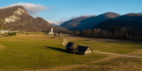 Minimalist Alpine Road in Bitnje Village: Traditional Kozolec Hayracks and Church at Sunset, Bohinj Valley Slovenia