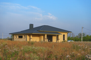 A modern brick house under construction in a new, environmentally friendly neighborhood.