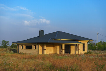 A modern brick house under construction in a new, environmentally friendly neighborhood.