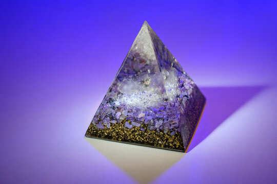 Orgonite pyramid with a crystal quartz on a colorful background.