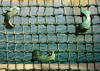 ryby na tle sieci, ryby w sieci, metalowa ryba na metalowej sieci wędkarskiej, metalowe ogrodzenie na wzór sieci z rybą,  fish from metal on a braided net background © kateej