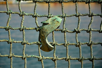 ryba na tle sieci, ryba w sieci, metalowa ryba na metalowej sieci wędkarskiej, metalowe ogrodzenie na wzór sieci z rybą,  fish from metal on a braided net background © kateej
