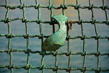 ryba na tle sieci, ryba w sieci, metalowa ryba na metalowej sieci wędkarskiej, metalowe ogrodzenie na wzór sieci z rybą,  fish from metal on a braided net background © kateej