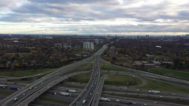 Aerial perspective of the don valley parkway and highway 401 interchange in toronto, showing heavy traffic moving through the complex road network with the city skyline in the background