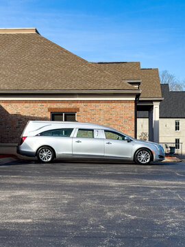 A silver hearse parked at Neal-Tarpley-Parchman (NTP) Funeral Home in Clarksville, TN, with copy space in the slightly cloudy, blue sky