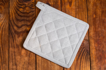 Gray quilted textile potholder on a dark rustic table