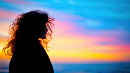 Fototapeta premium Silhouette of a person at sunset by the ocean with colorful sky