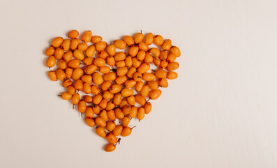 Fototapeta premium Sea Buckthorn Berries Heart Shape on Light Background