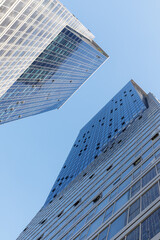 Modern glass skyscrapers photographed from a low angle against a clear blue sky.