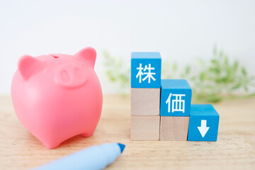 豚の貯金箱と株価下落を示す青ブロック。