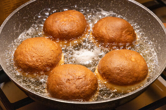Golden brown doughnuts frying in hot oil pan for traditional Fat Thursday celebration homemade sweet pastry dessert cooking process and delicious culinary snack background.