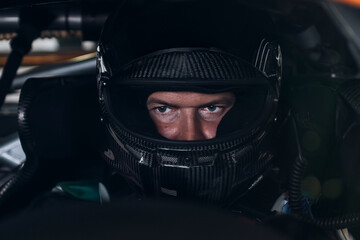 Racing Driver in Carbon Fiber Helmet Sitting Inside Race Car Cockpit During Track Day