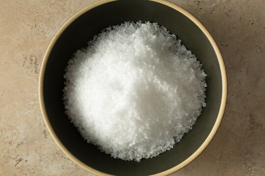 A top down view of a bowl of crystal sea salt flakes.