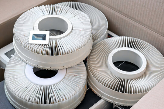 A box of vintage slide projector trays holding two inch slides of photographs designed for viewing on a slide projector, with one slide out of it's space sitting on top.