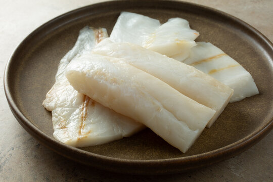 A view of several raw orange roughy filets, on a plate.