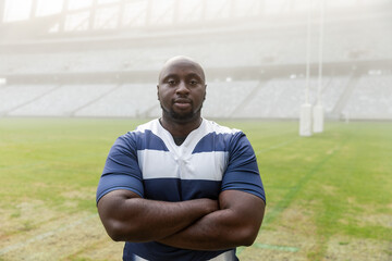 Rugby goalposts are standing on marked grass pitch inside large covered stadium, with hazy stands