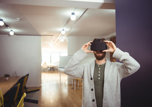 Smartphone being held and used as VR viewer in coworking space with long wooden table